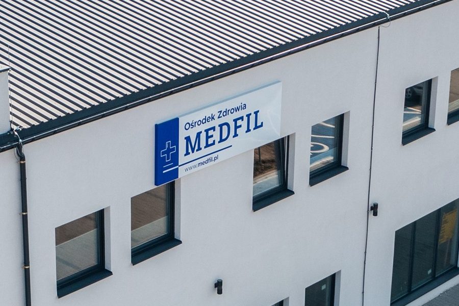 Tablica Ośrodek Zdrowia MEDFIL na ścianie budynku przy ulicy Białostockiej 1A w Juchnowcu Górnym