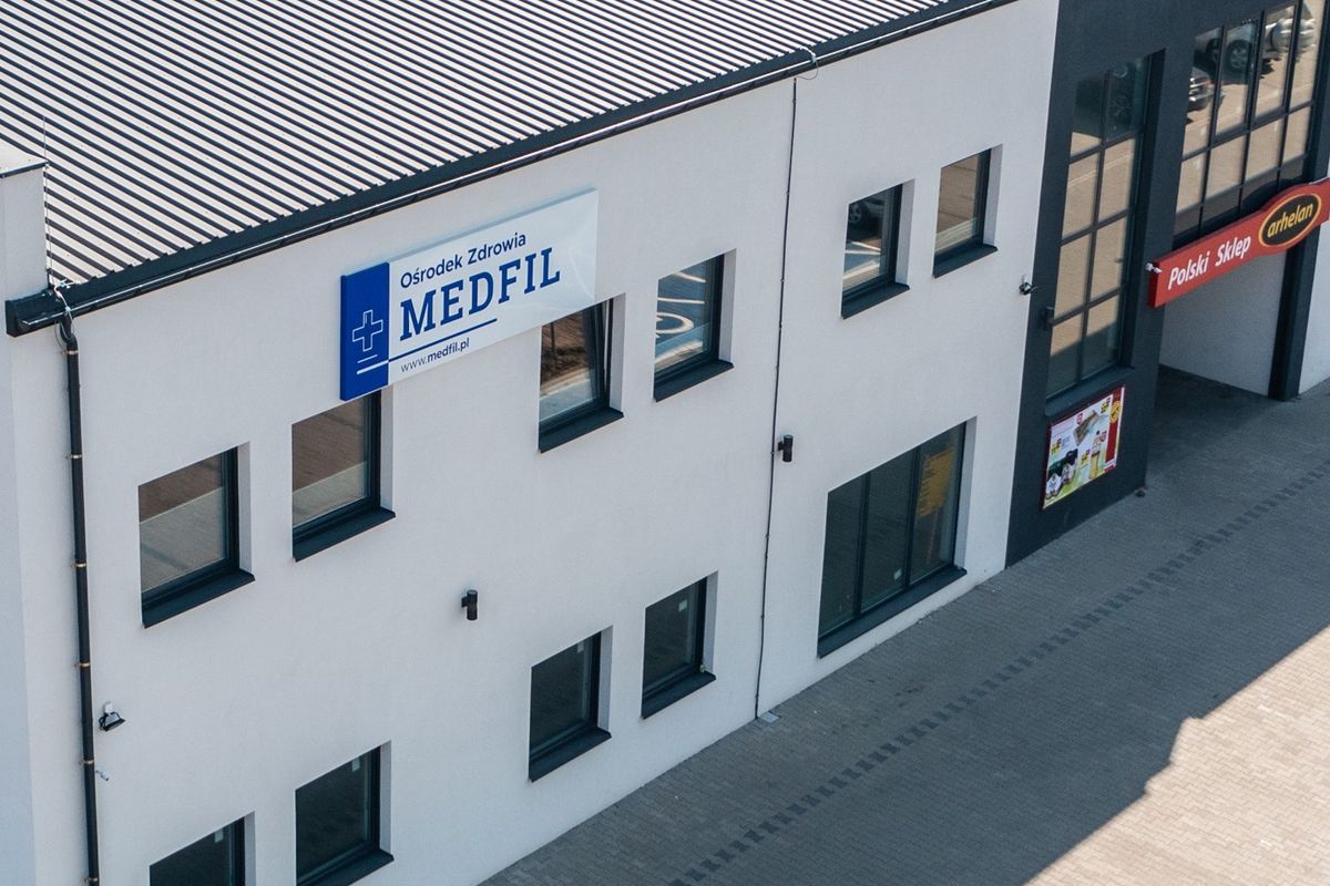 Budynek przychodni z tablicą Ośrodek Zdrowia MEDFIL nad wejściem